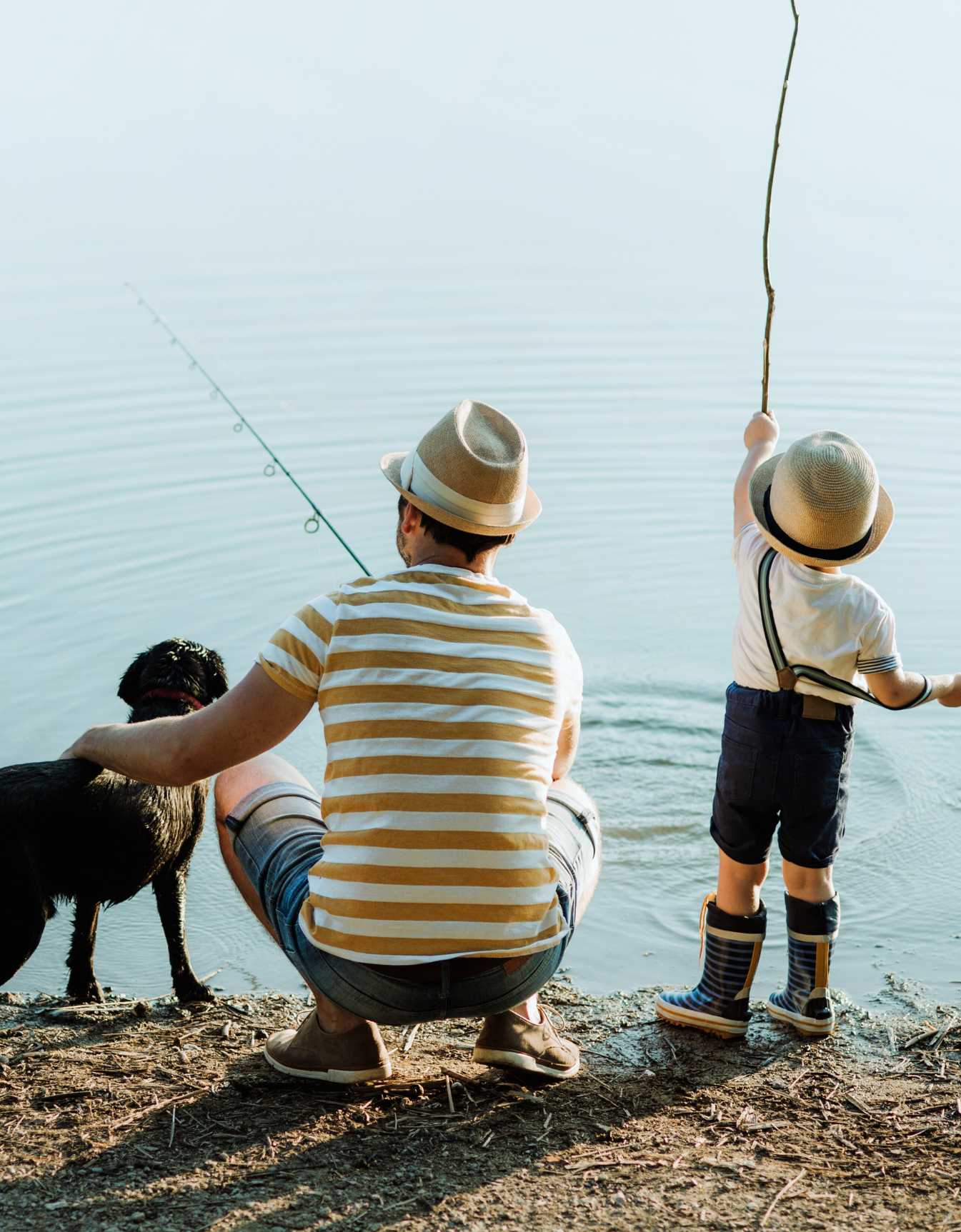 A father and young son fishing with their dog on the banks of the Kiawah River in the Johns Island community at sunset