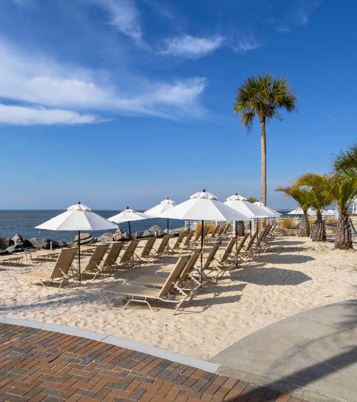Luxury oceanfront beach club at Seabrook Island featuring lounge chairs, white umbrellas, and a resort-style swimming pool overlooking the ocean.