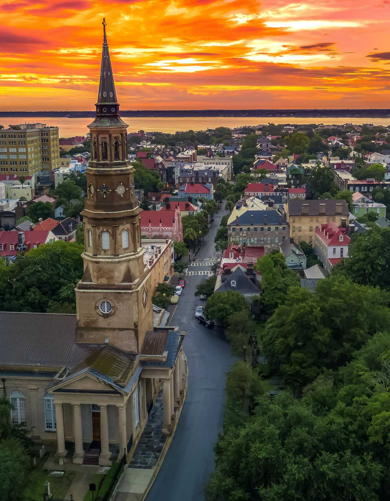 Aerial sunset view of historic downtown Charleston and a prominent church steeple.