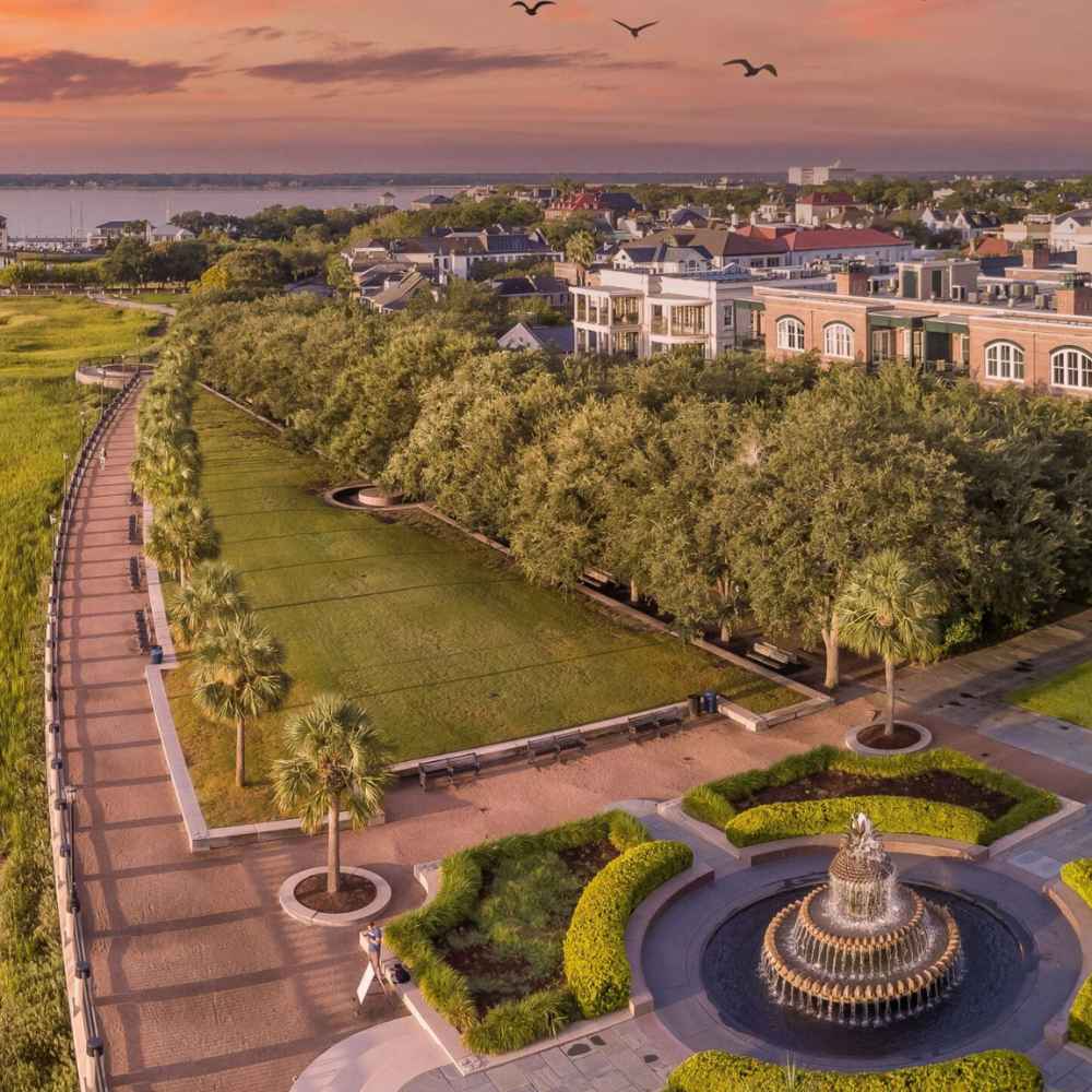 Panoramic aerial view of the historic Battery waterfront in Charleston, South Carolina, showing coastal homes at sunset.
