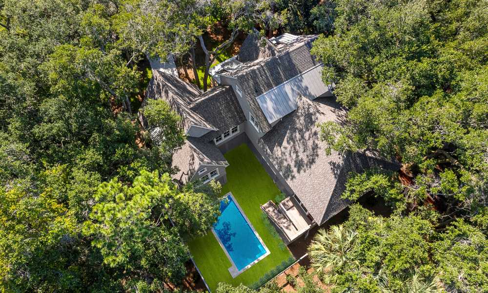 Aerial view of a luxury Charleston SC Lowcountry home with a swimming pool surrounded by lush trees